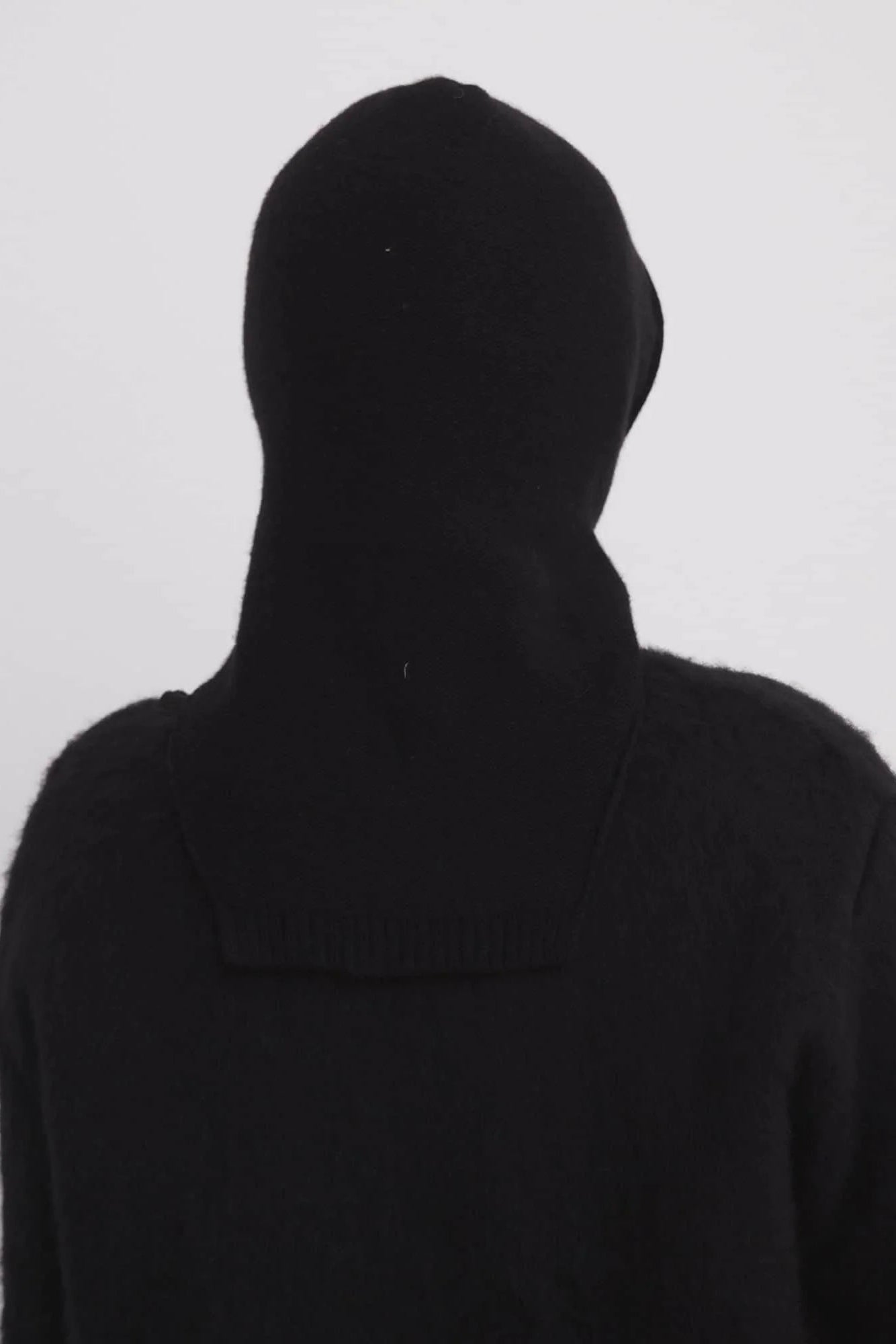 Person wearing a black hooded garment against a white background