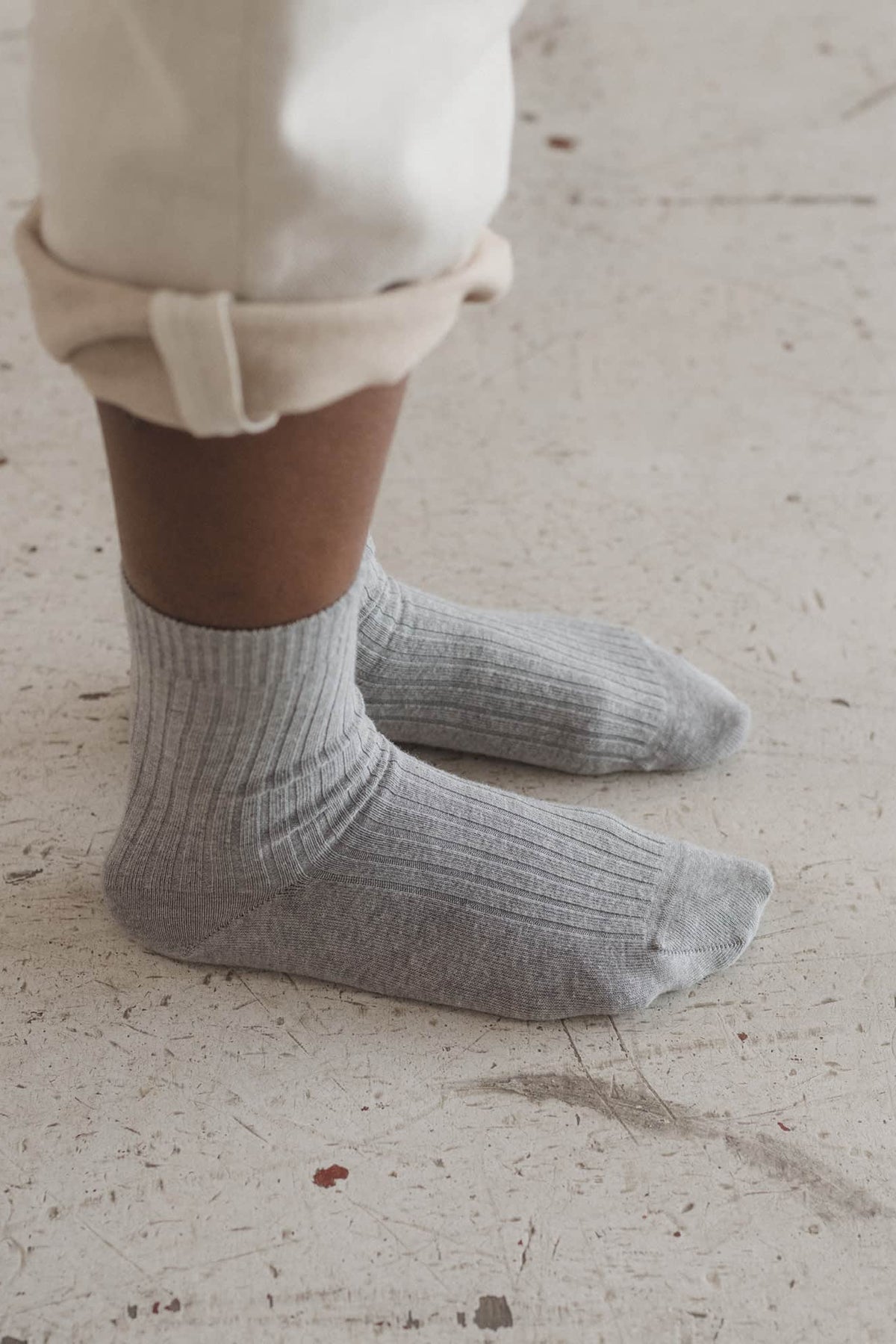 Person wearing light gray socks on a textured floor