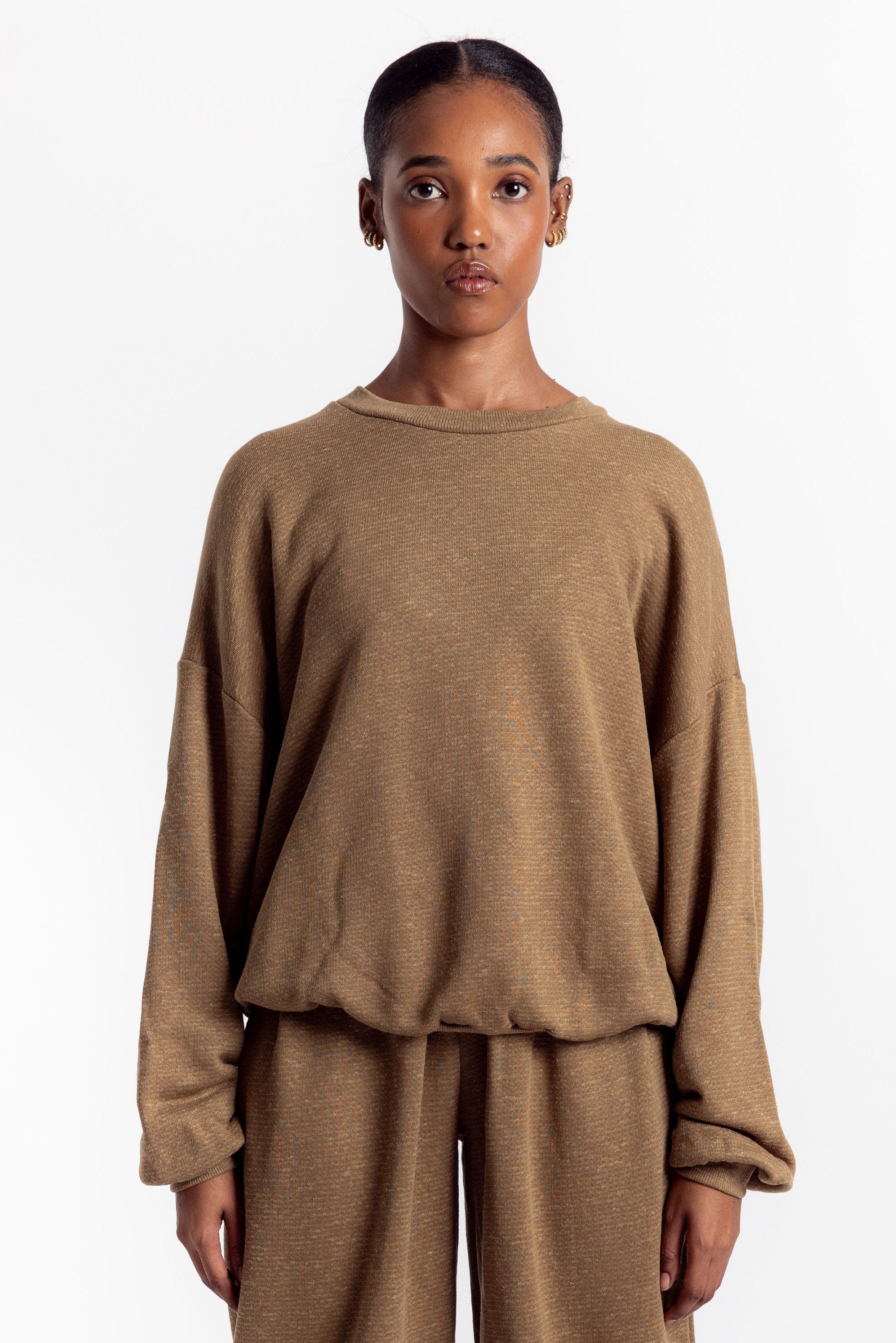 Person wearing a brown outfit with beige boots on a white background