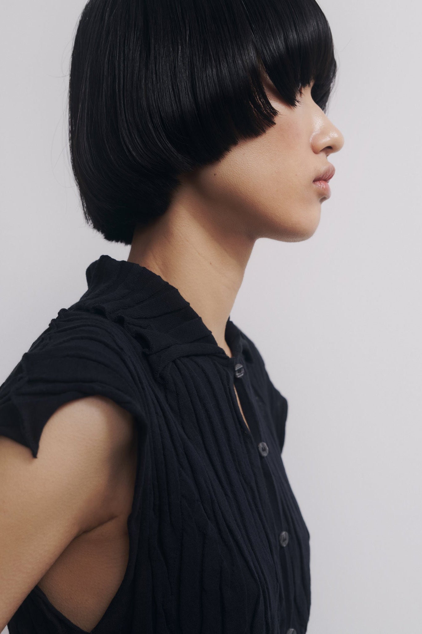 Person with a stylish black bob haircut against a plain background
