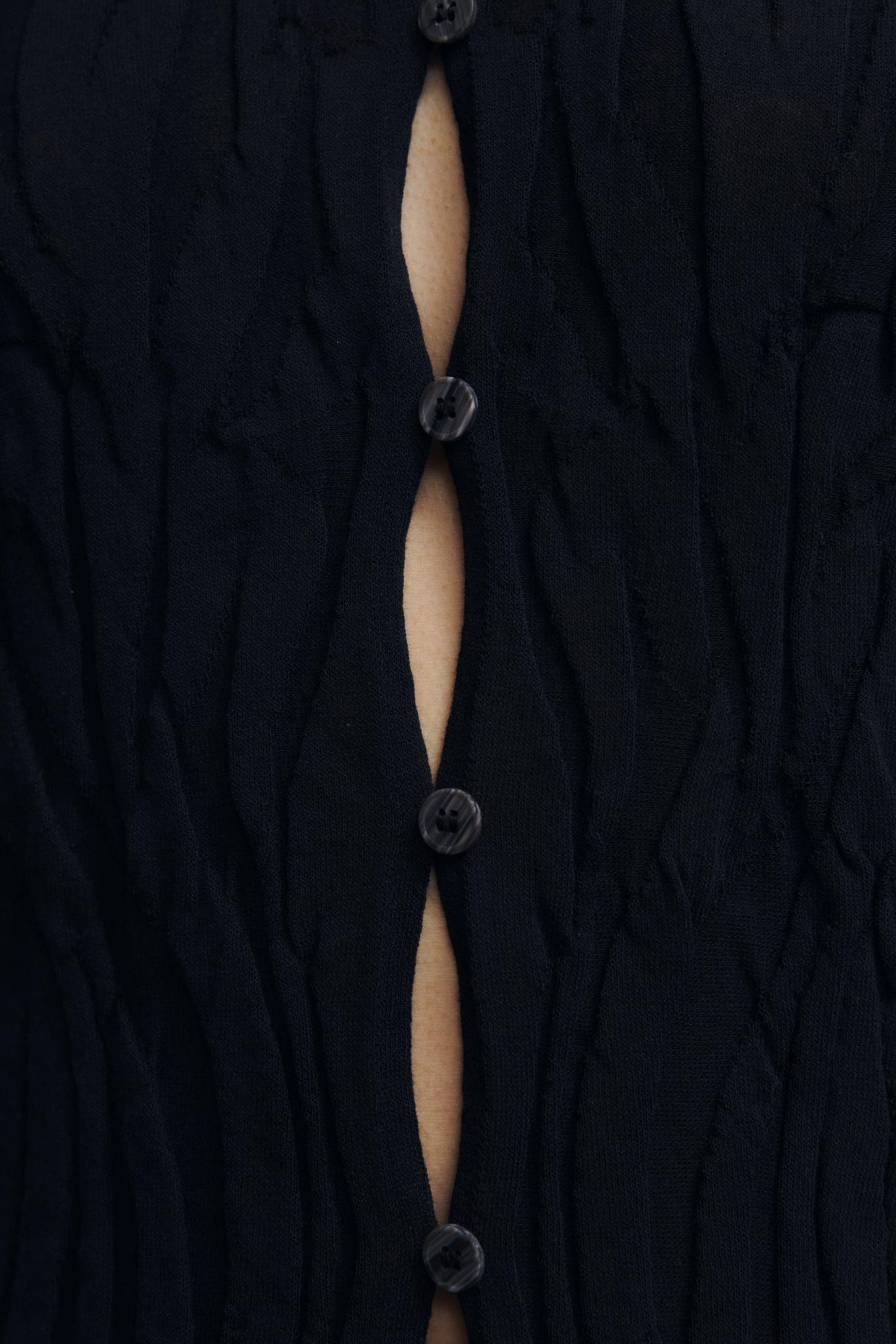 Close-up of a black buttoned garment with a visible seam.