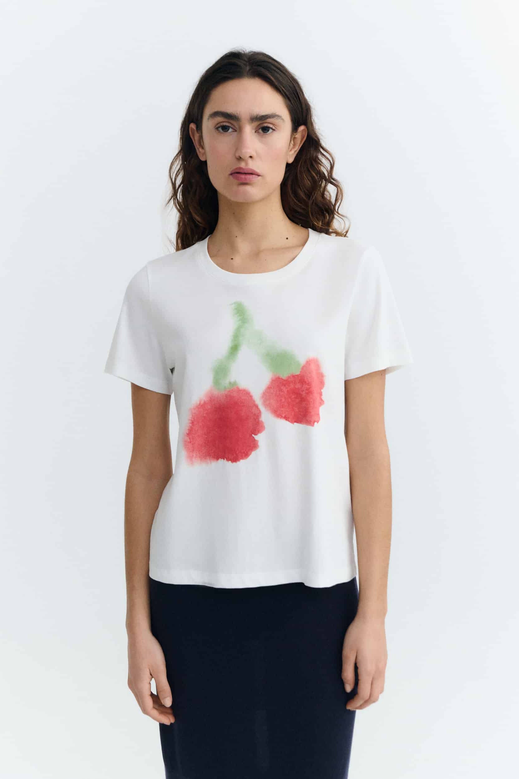 Woman wearing a white t-shirt with red cherry design on a white background