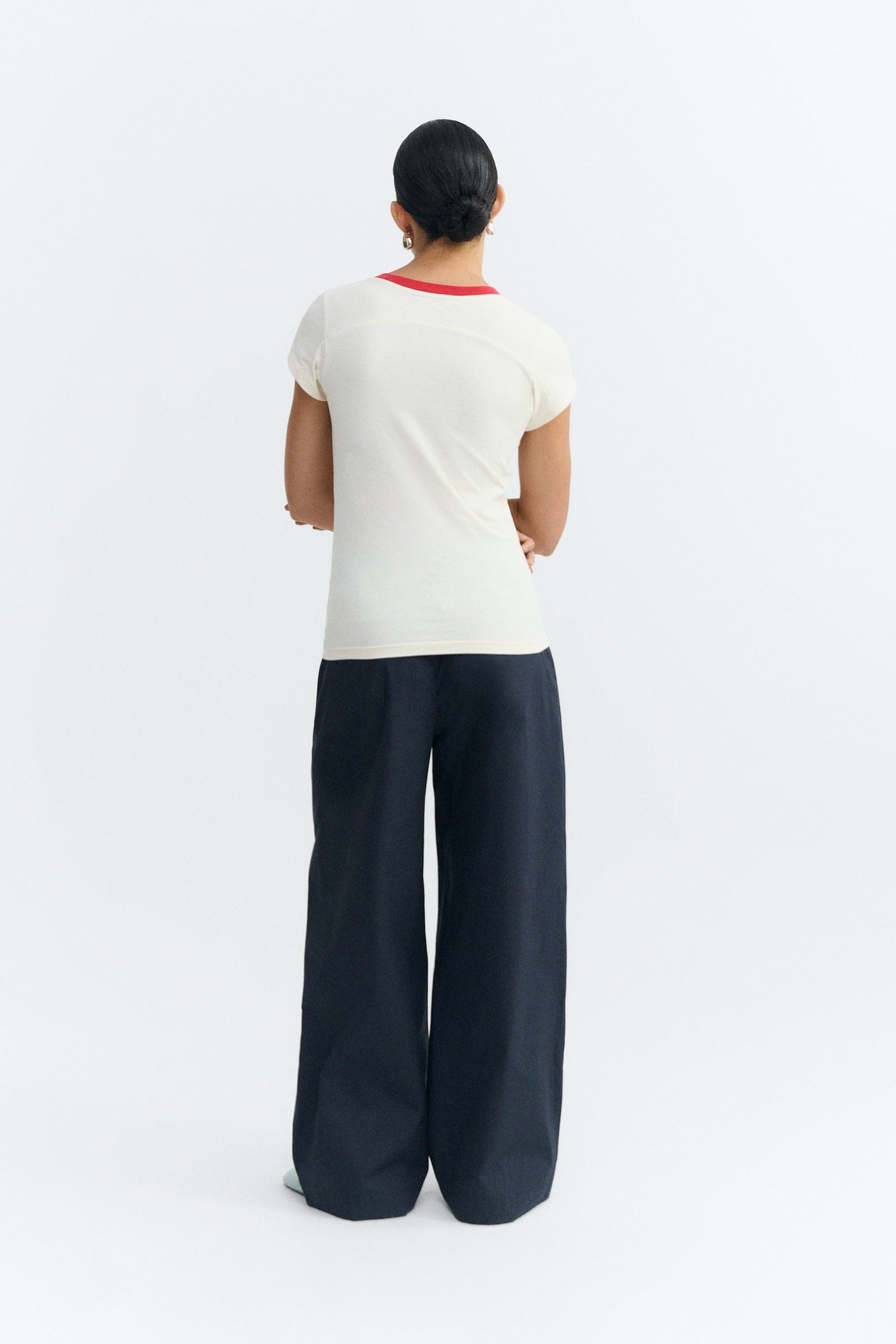 Person wearing a white t-shirt and dark blue pants on a white background