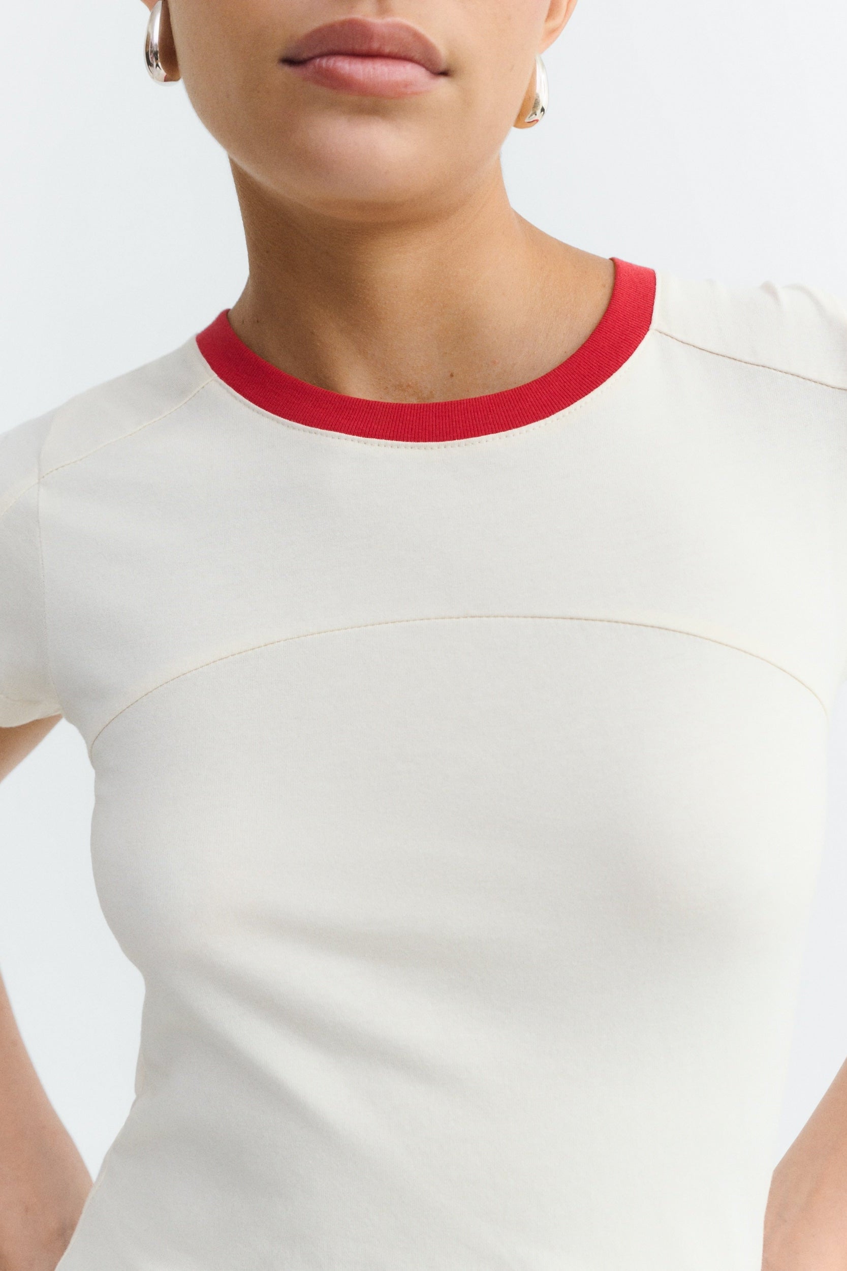 White t-shirt with red neckline worn by a person on a white background