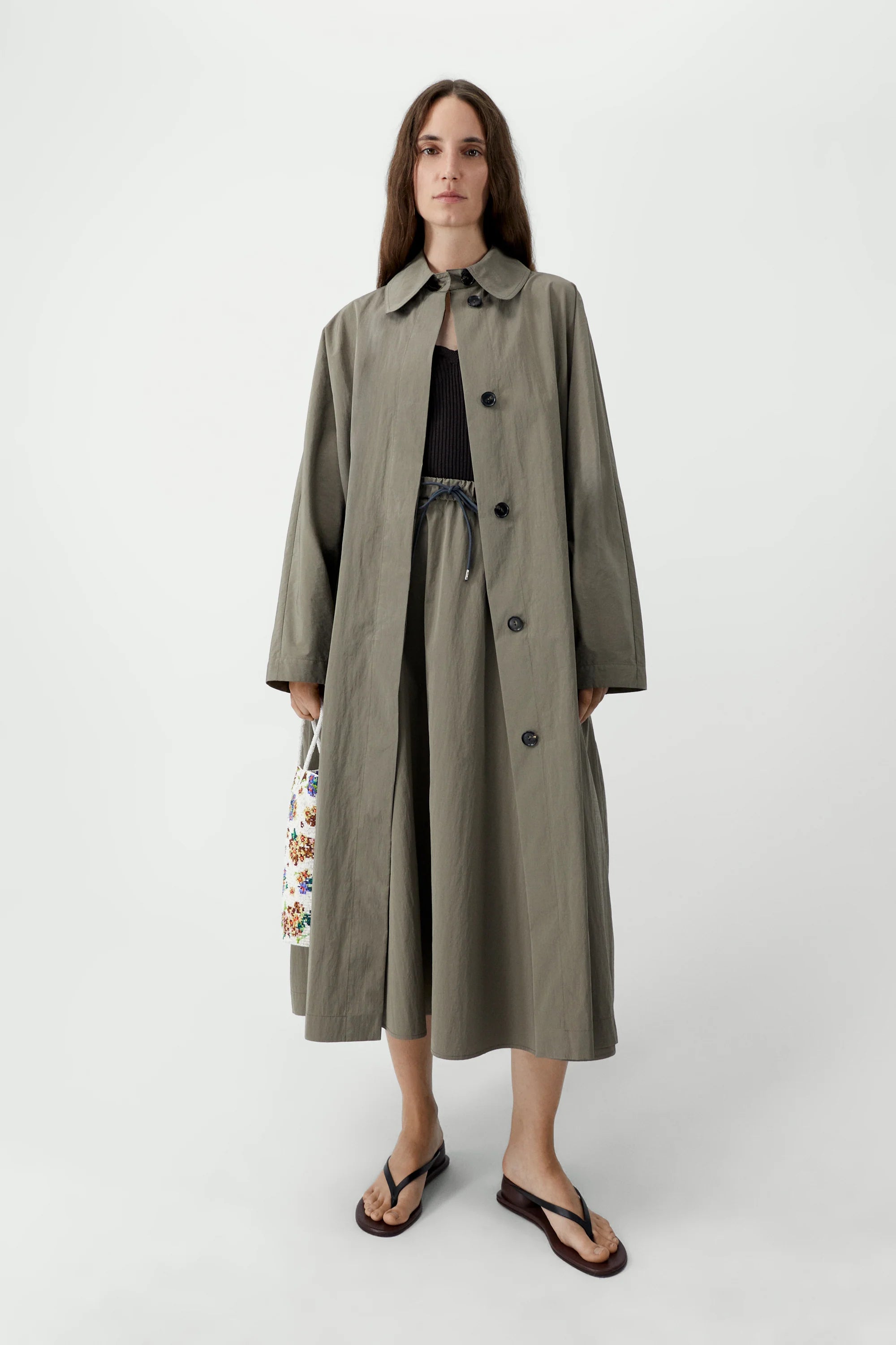 Woman wearing a long beige trench coat on a white background