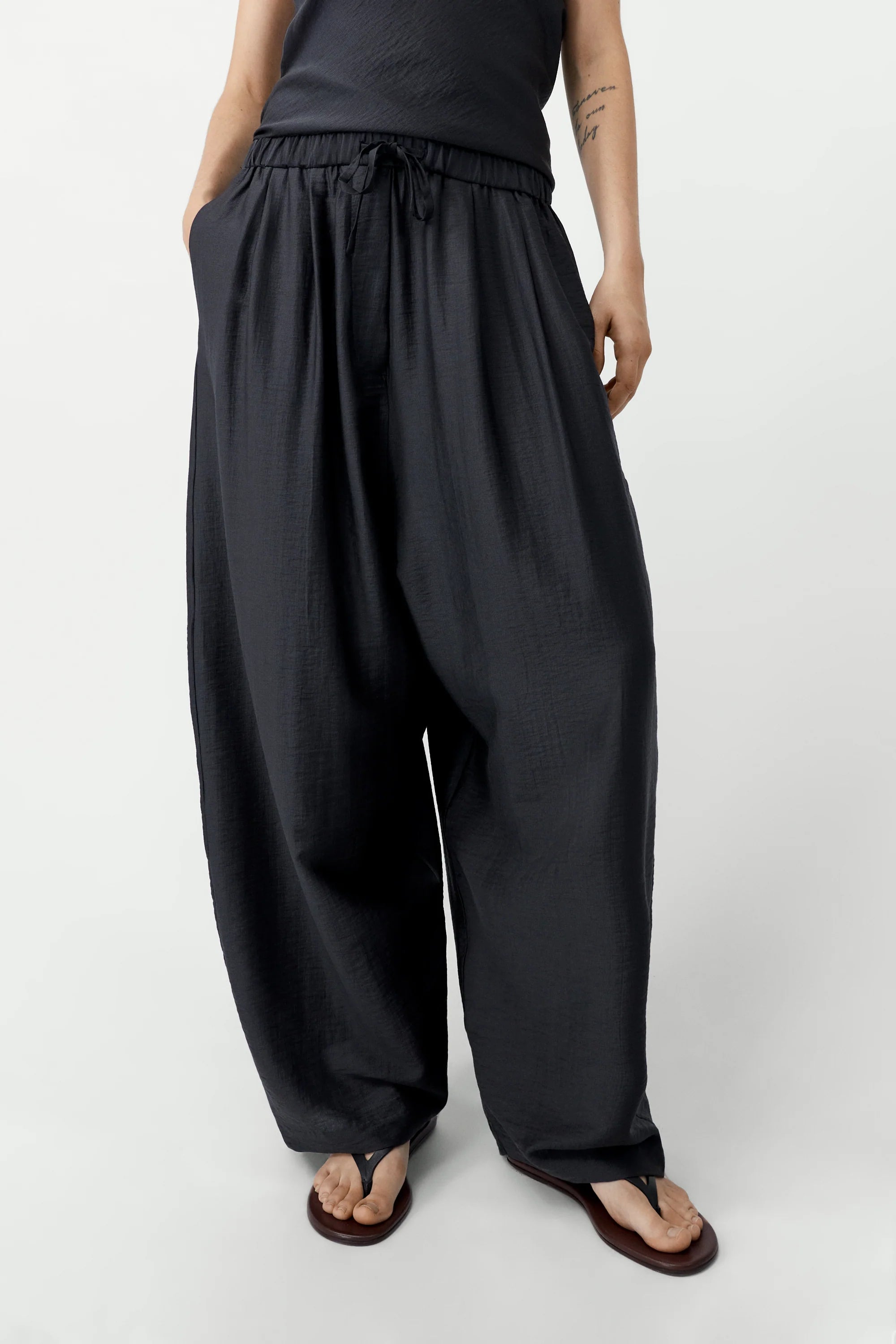 Person wearing black wide-leg pants and a black top on a white background