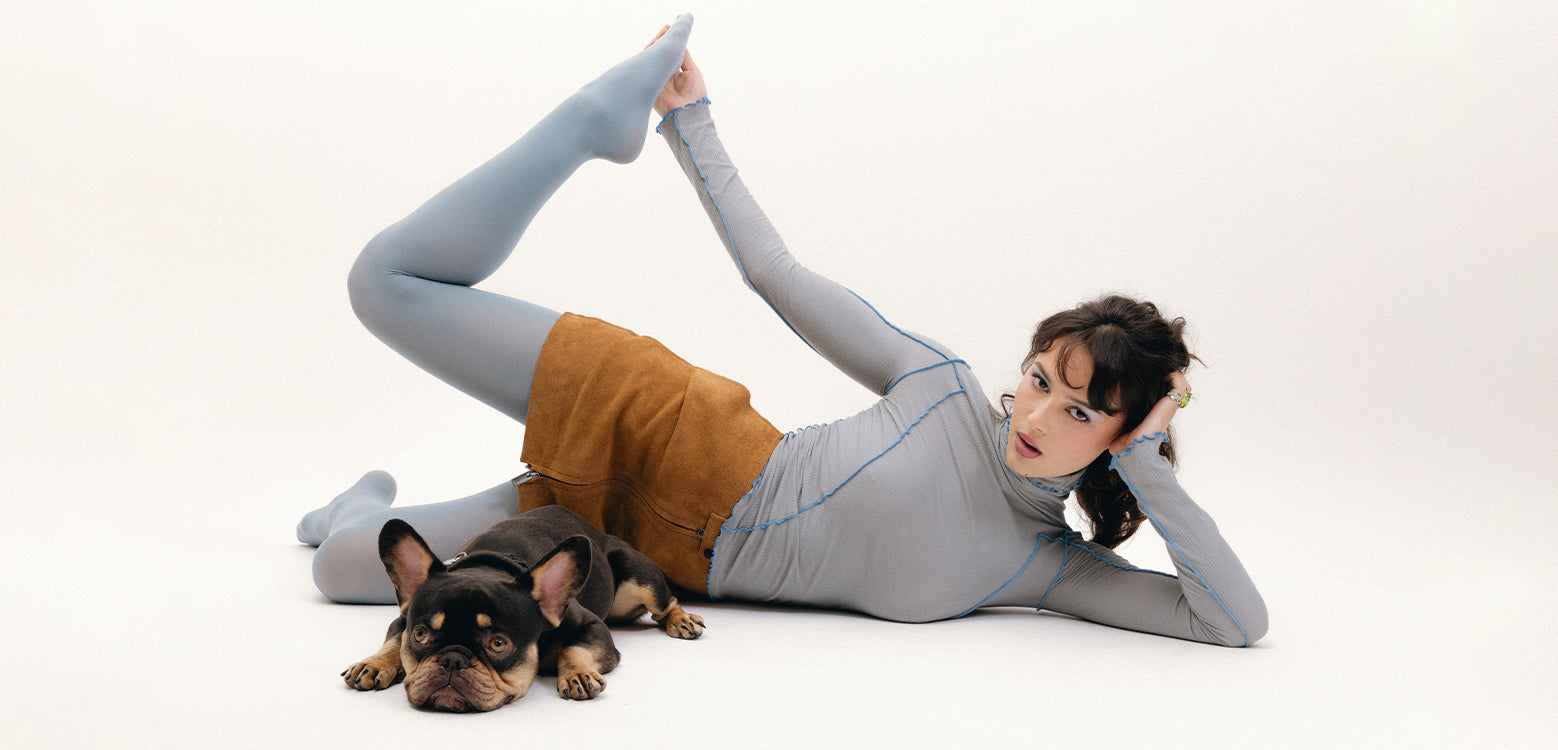 Woman in a yoga pose with a small dog on a white background
