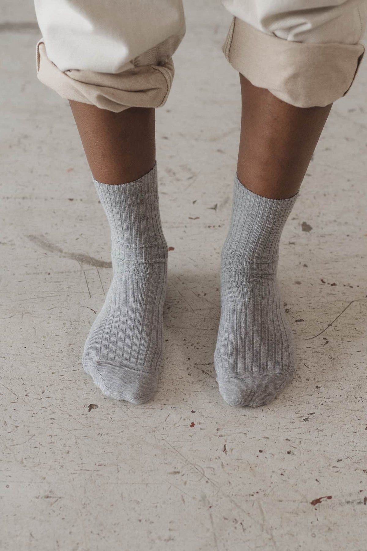 Person wearing light gray socks and beige pants on a light-colored floor.
