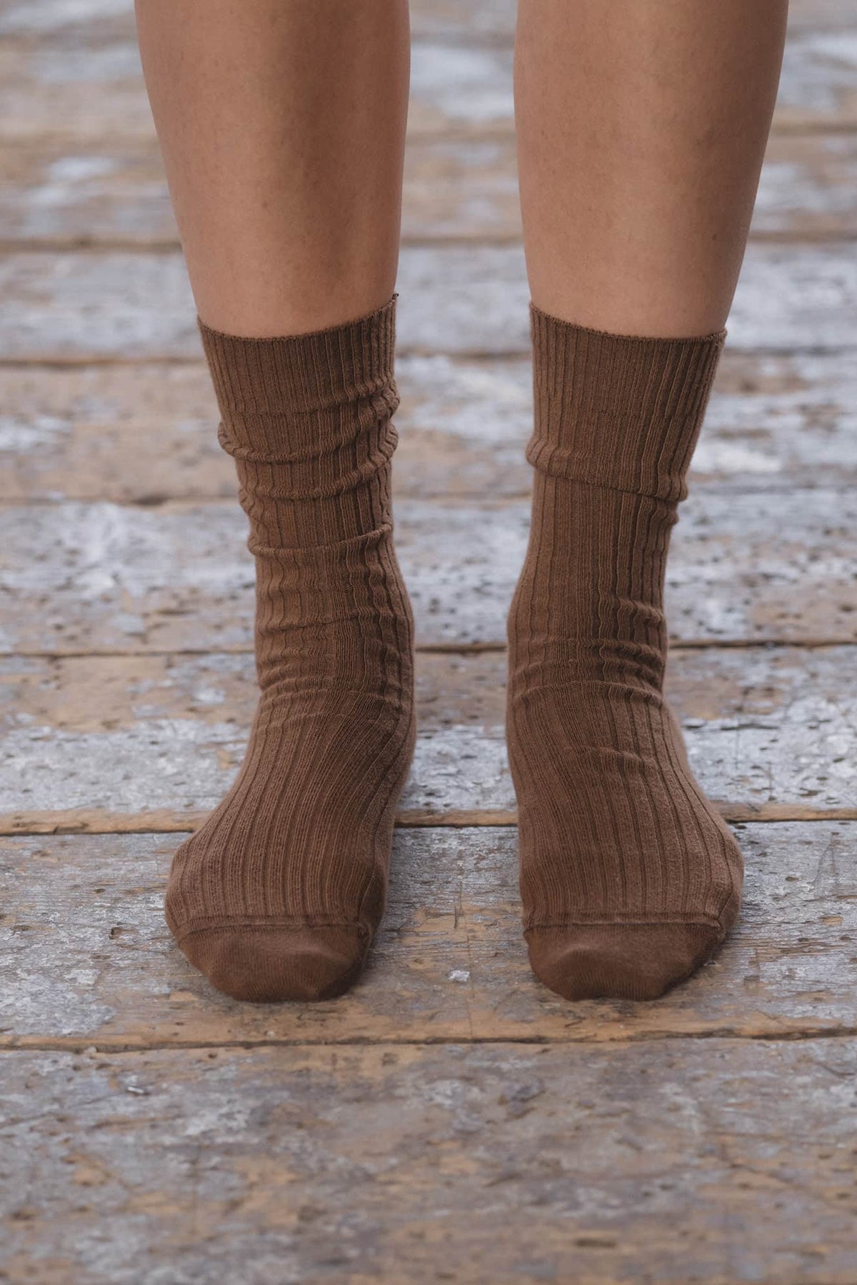 Brown ribbed socks worn on a wooden floor