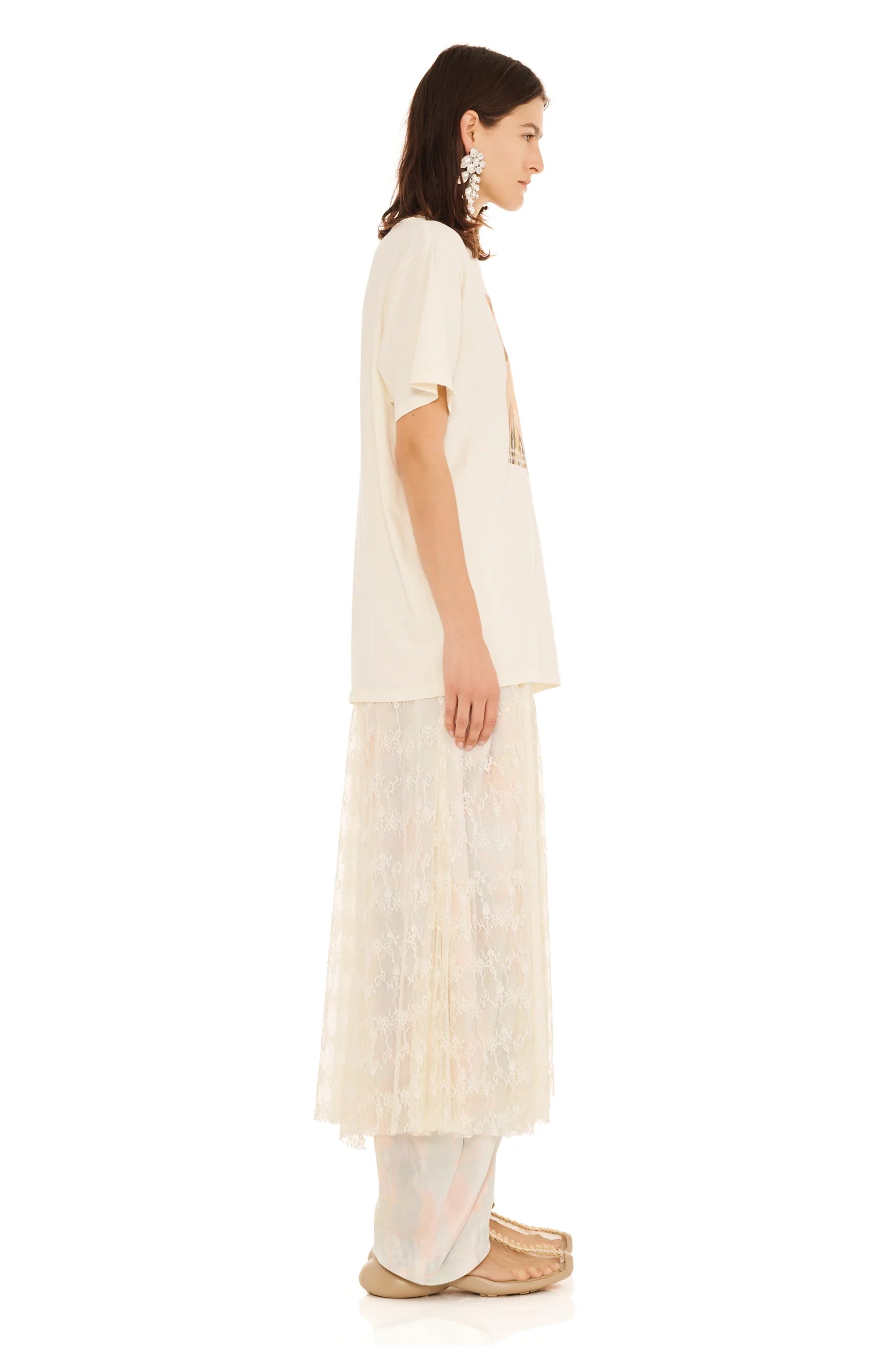 Woman wearing a long, light-colored dress with a plain background