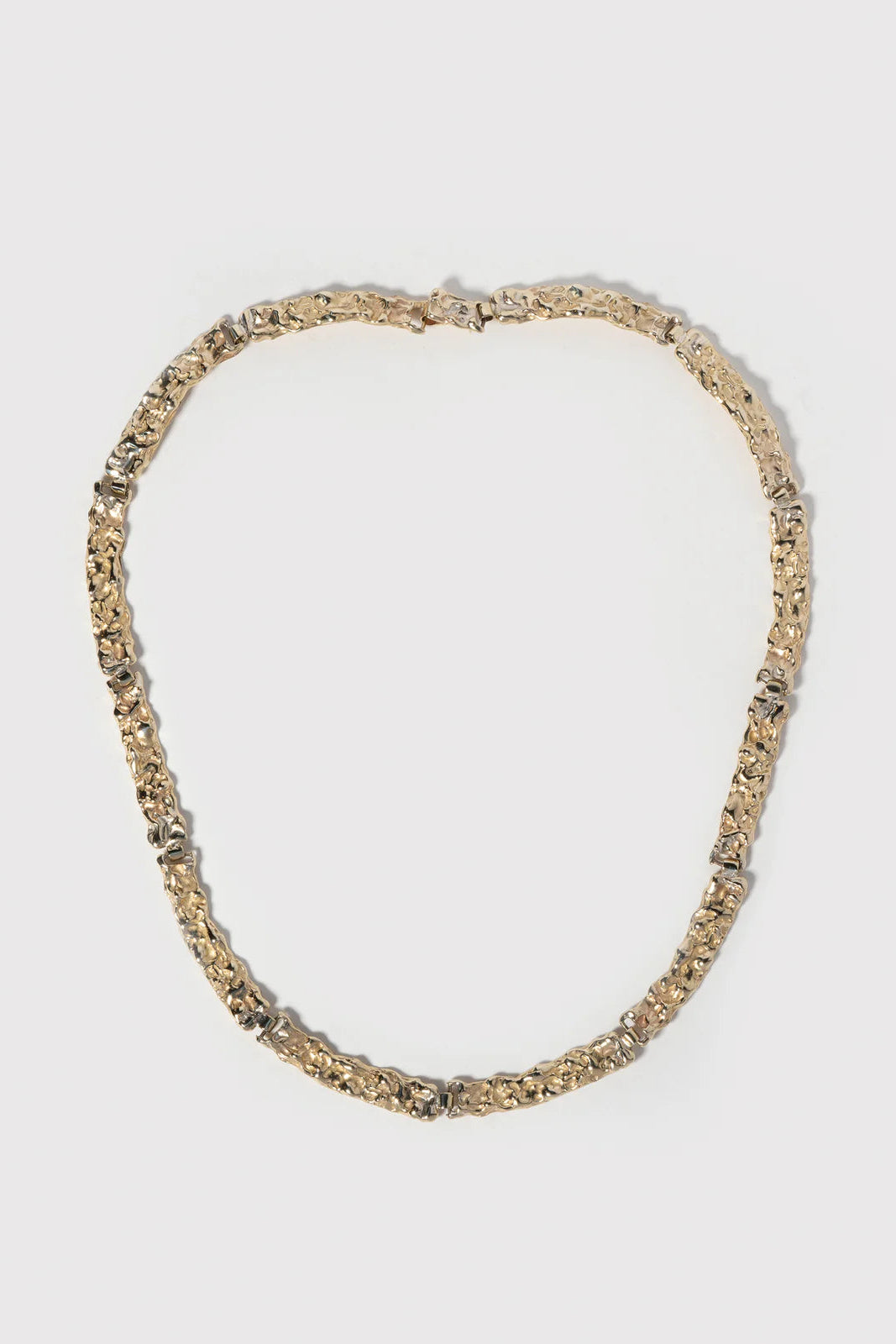 Gold necklace on a light gray background