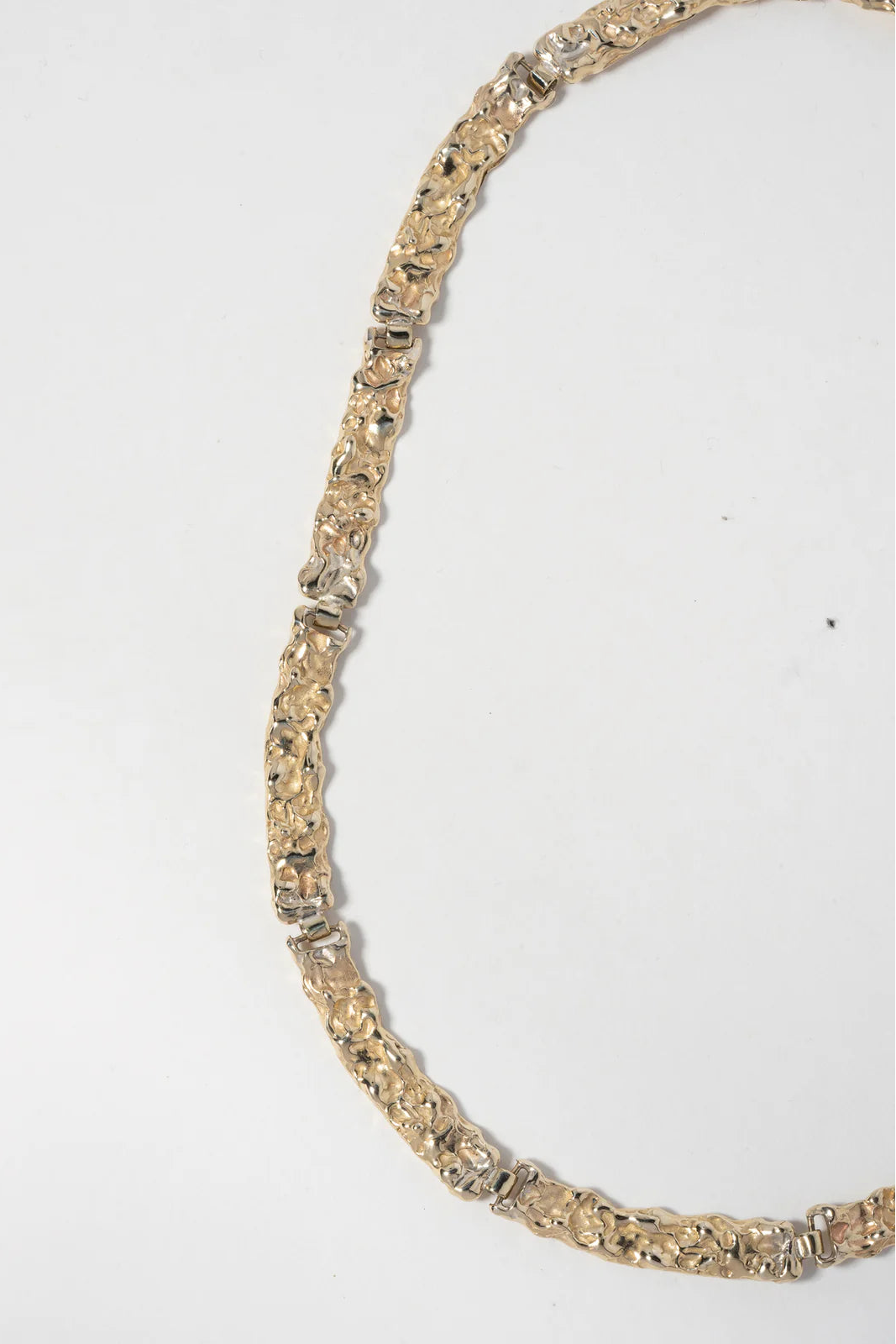 Gold necklace with embedded stones on a white background