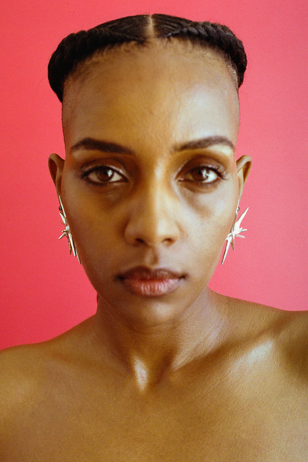 Woman with braided hair against a pink background