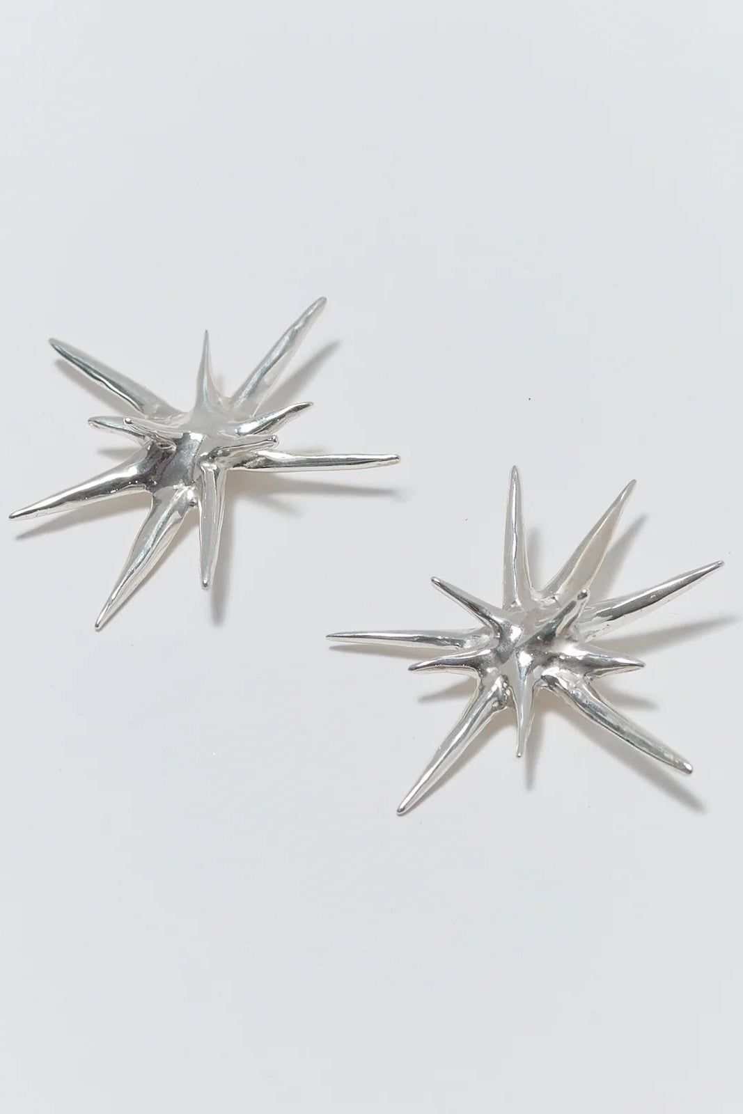 Pair of silver star-shaped earrings on a white background