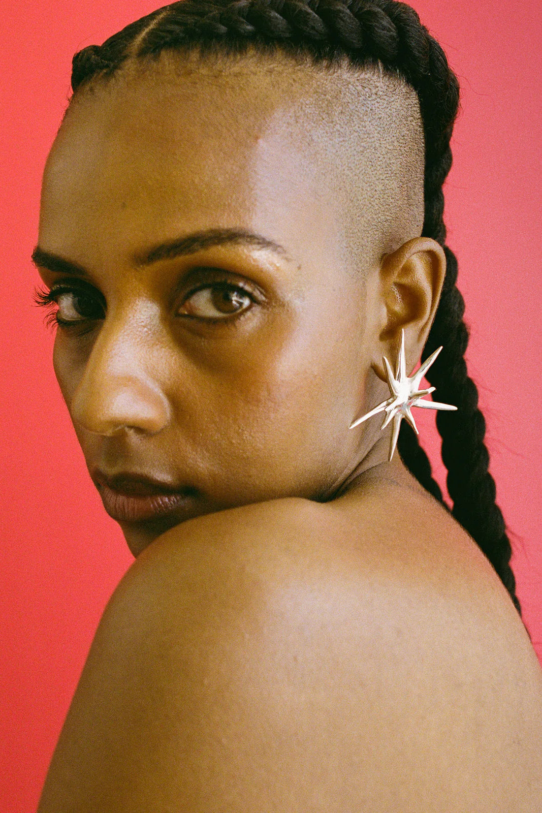 Woman with braided hair against a red background