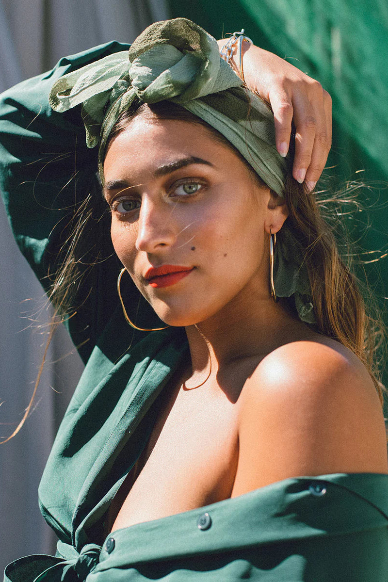 Woman wearing a green headscarf and coat with a blurred background