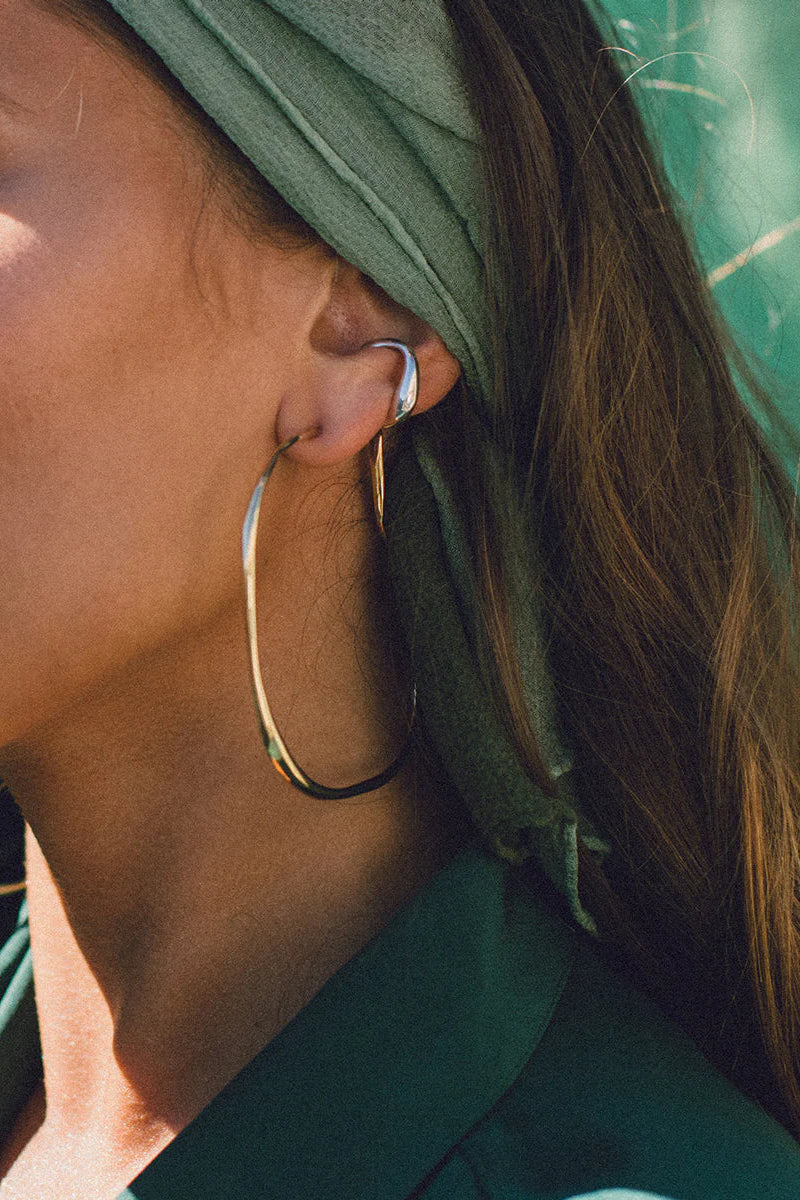 Close-up of a person wearing a green headscarf and gold hoop earrings.