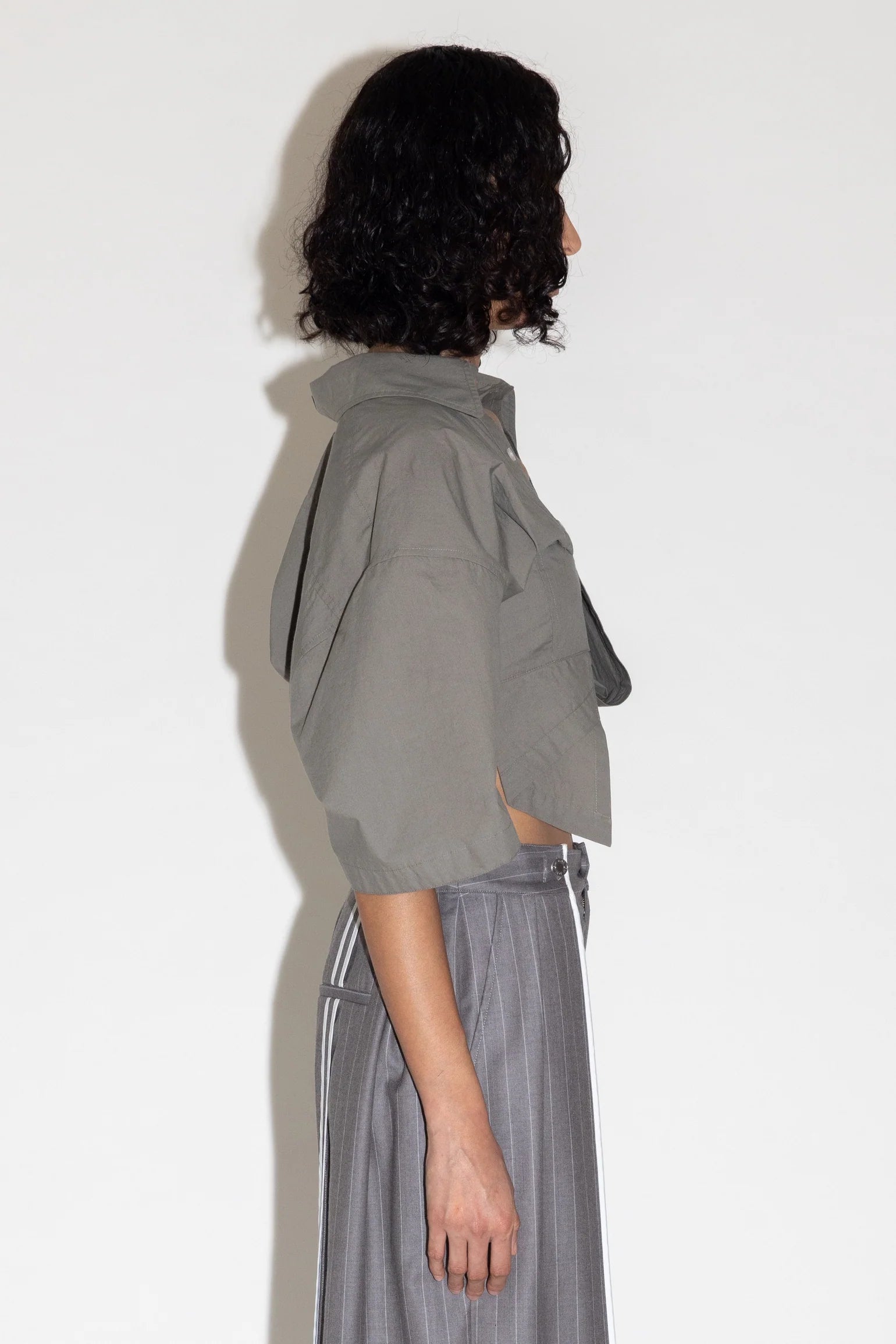 Person wearing a gray jacket and pants against a white background