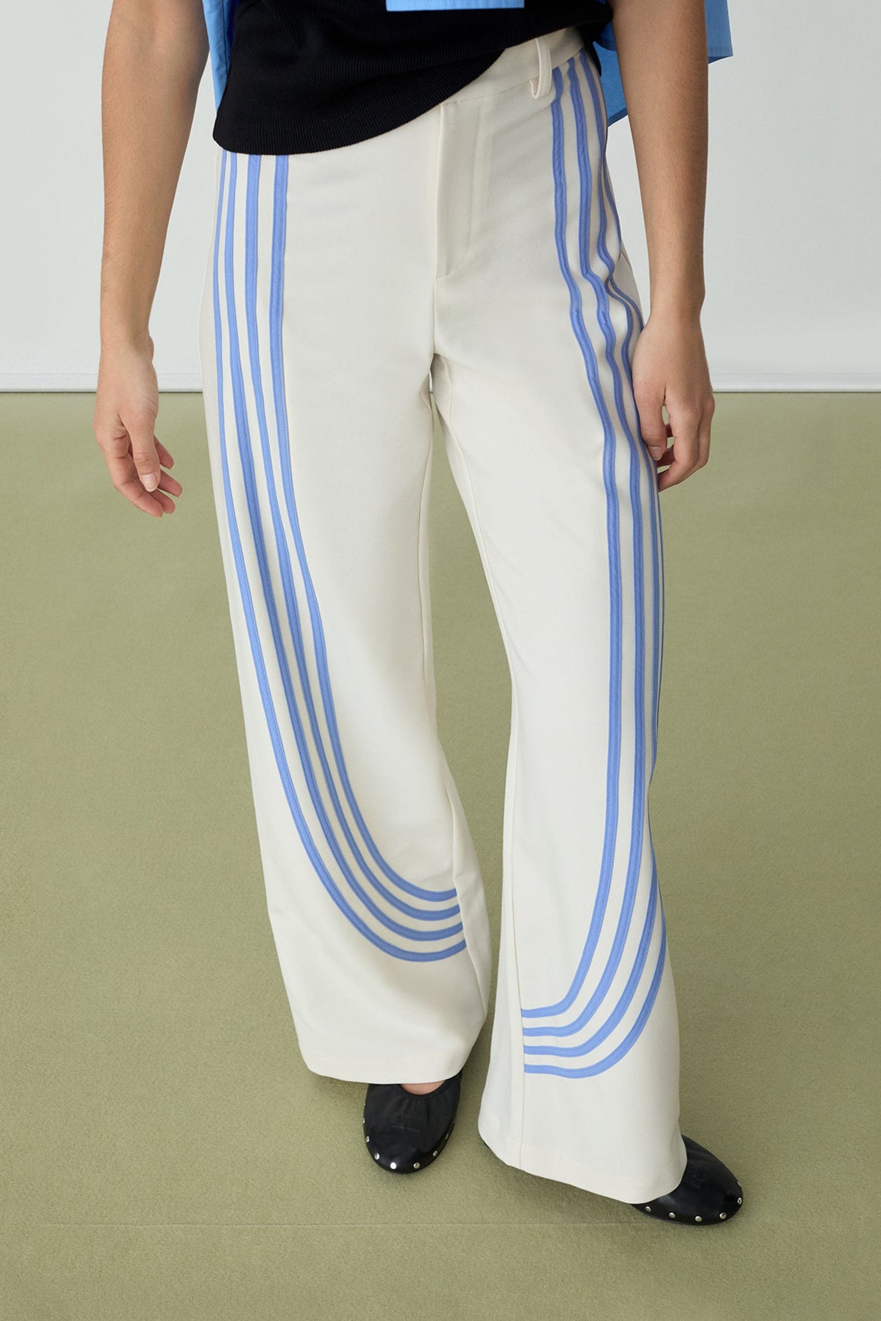 White pants with blue stripes worn by a person on a green floor.
