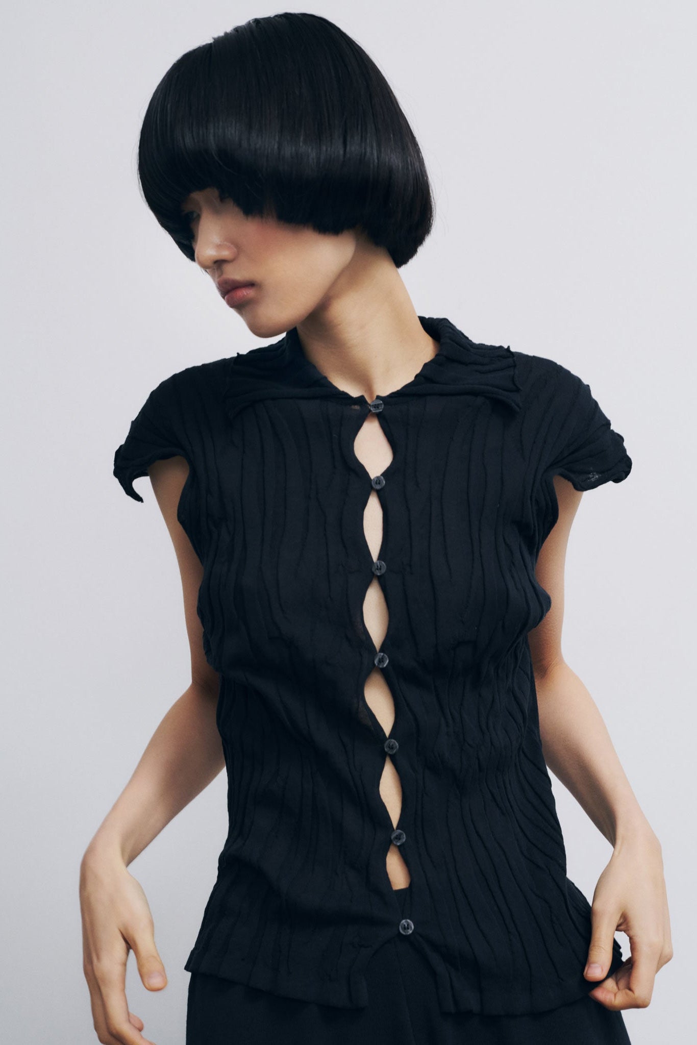 Black sleeveless top with cut-out design on a plain background