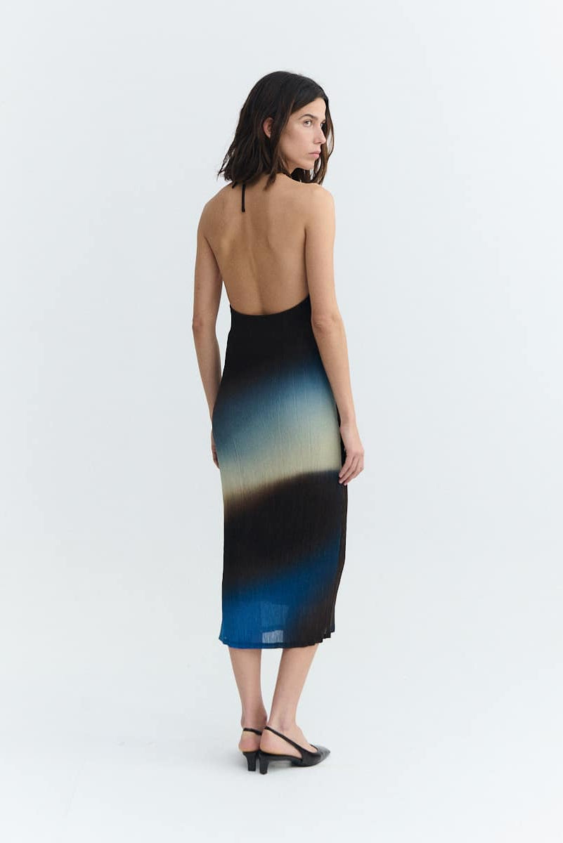 Woman wearing a gradient dress with black, blue, and green colors on a white background