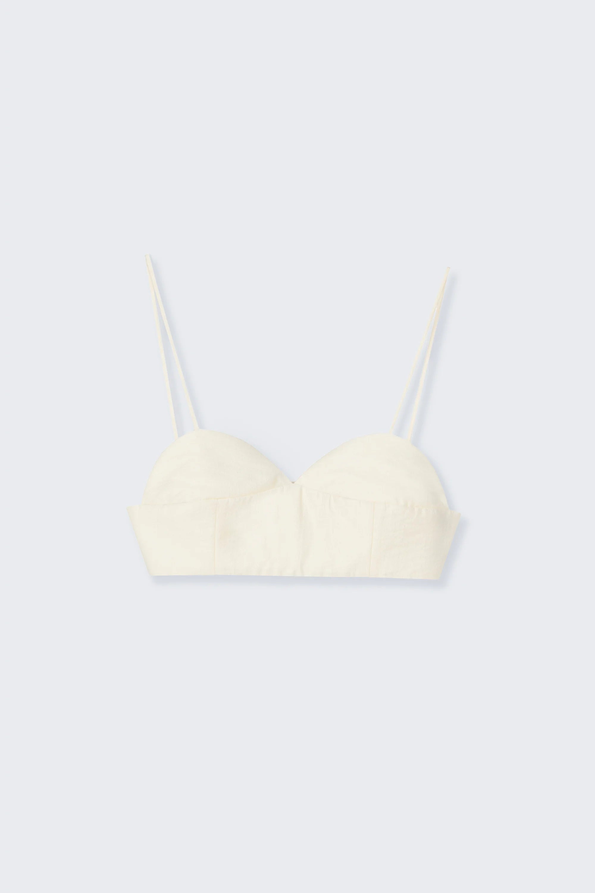 Cream-colored bralete top with thin straps on a light gray background