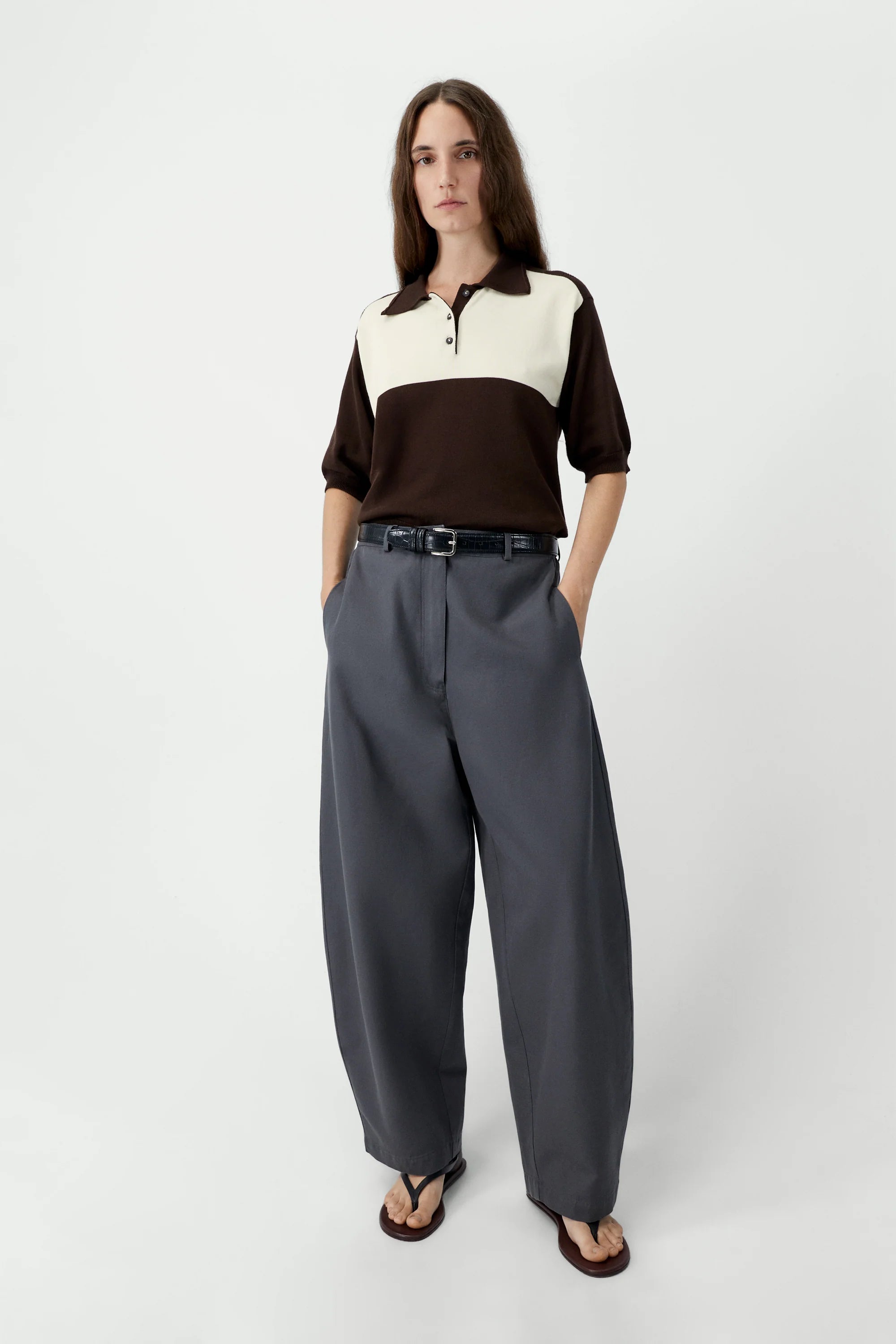 Woman wearing a two-tone shirt and gray pants on a white background