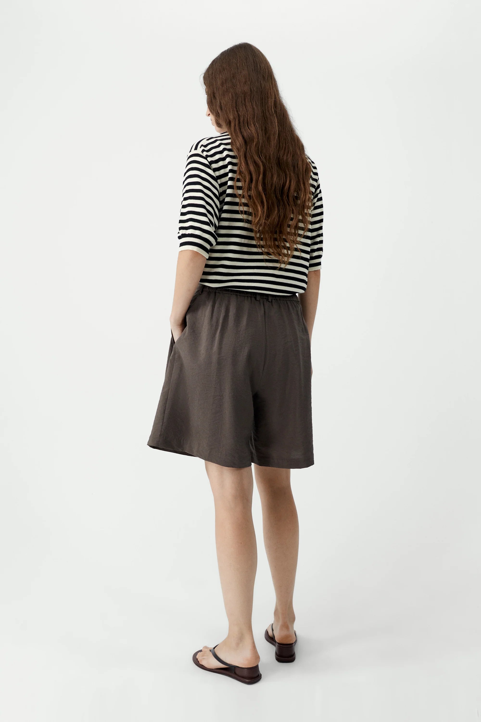 Woman wearing a striped shirt and brown shorts on a white background