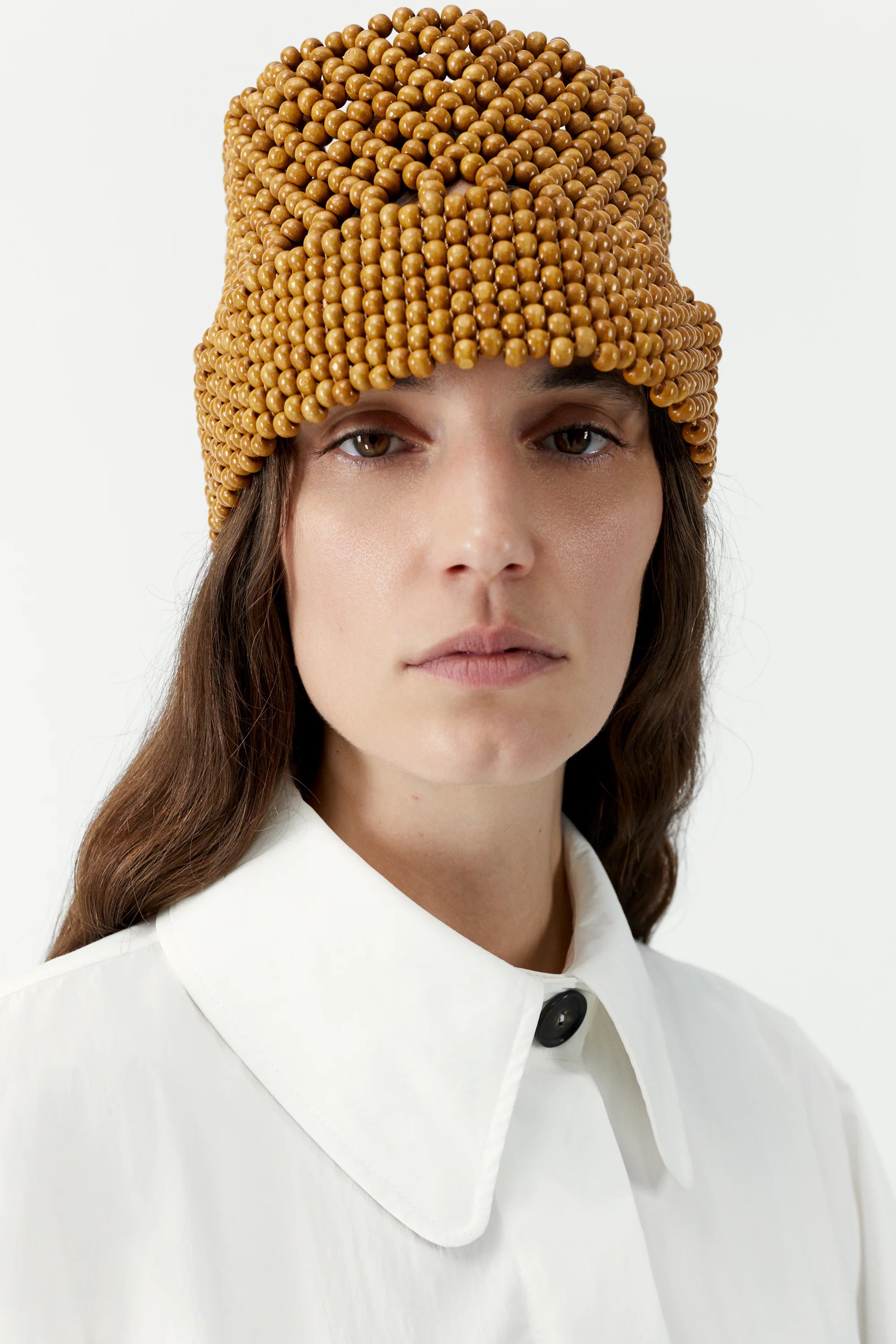 Woman wearing a mustard yellow beanie against a white background
